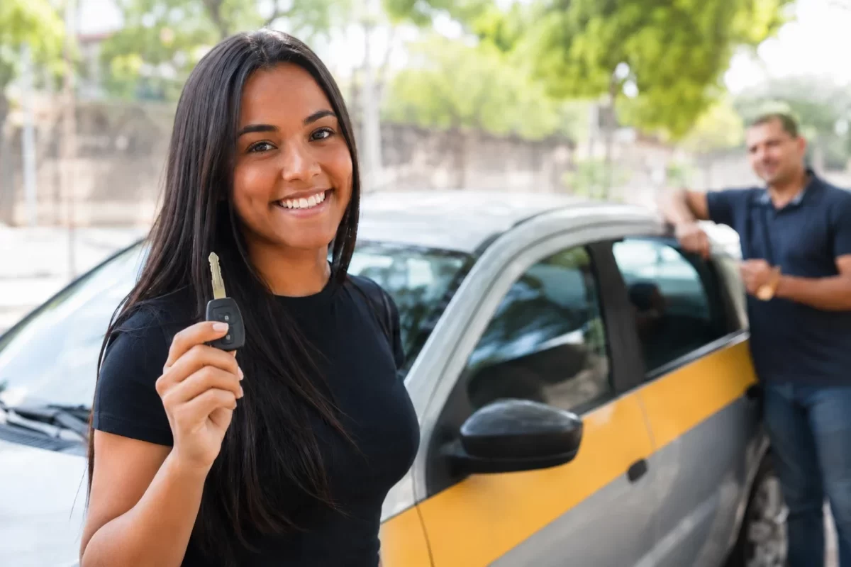 Aluna comemorando aprovação na autoescola com a chave do carro em mãos