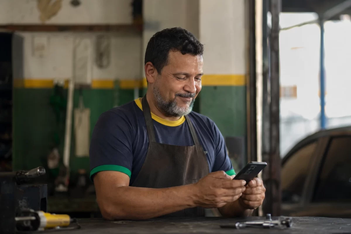 Mecânico respondendo cliente pelo WhatsApp na oficina