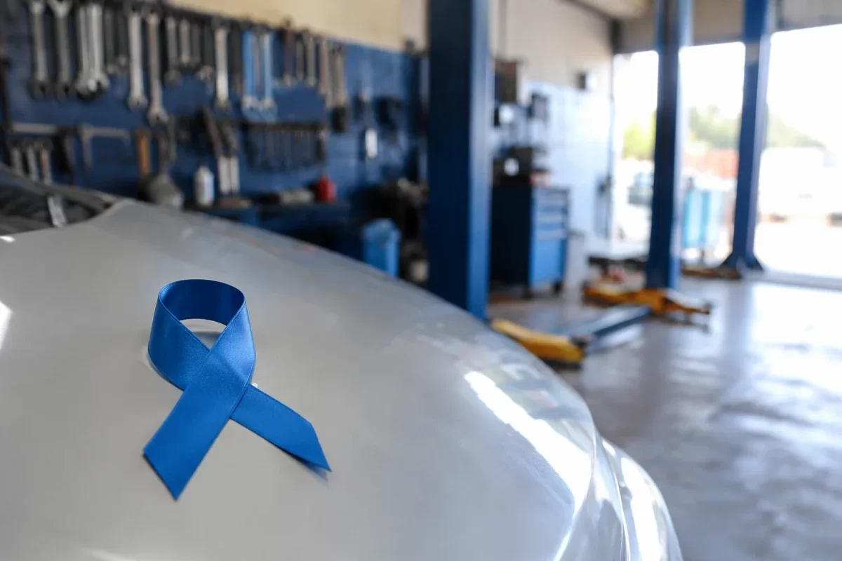 Laço azul do Novembro Azul sobre o capô de um carro na oficina